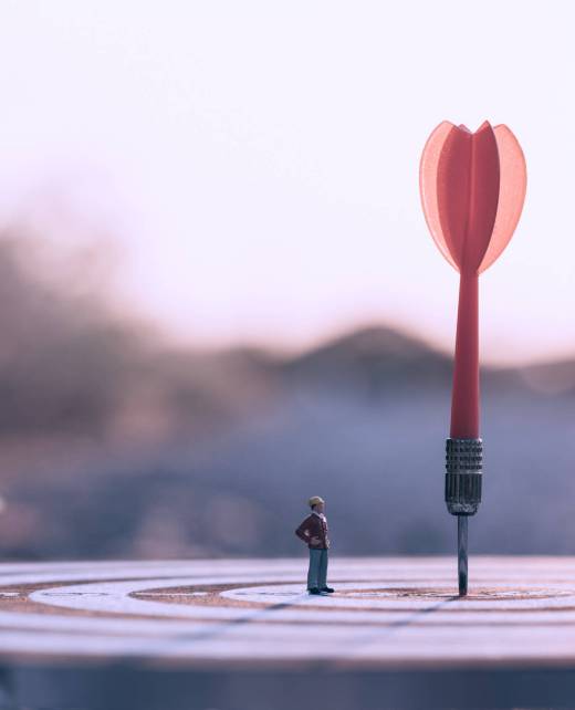 Businessman standing lookup red dart arrow hitting target centre Businessman standing lookup red dart arrow hitting target centre dartboard on sunset background. Business targeting and focus.